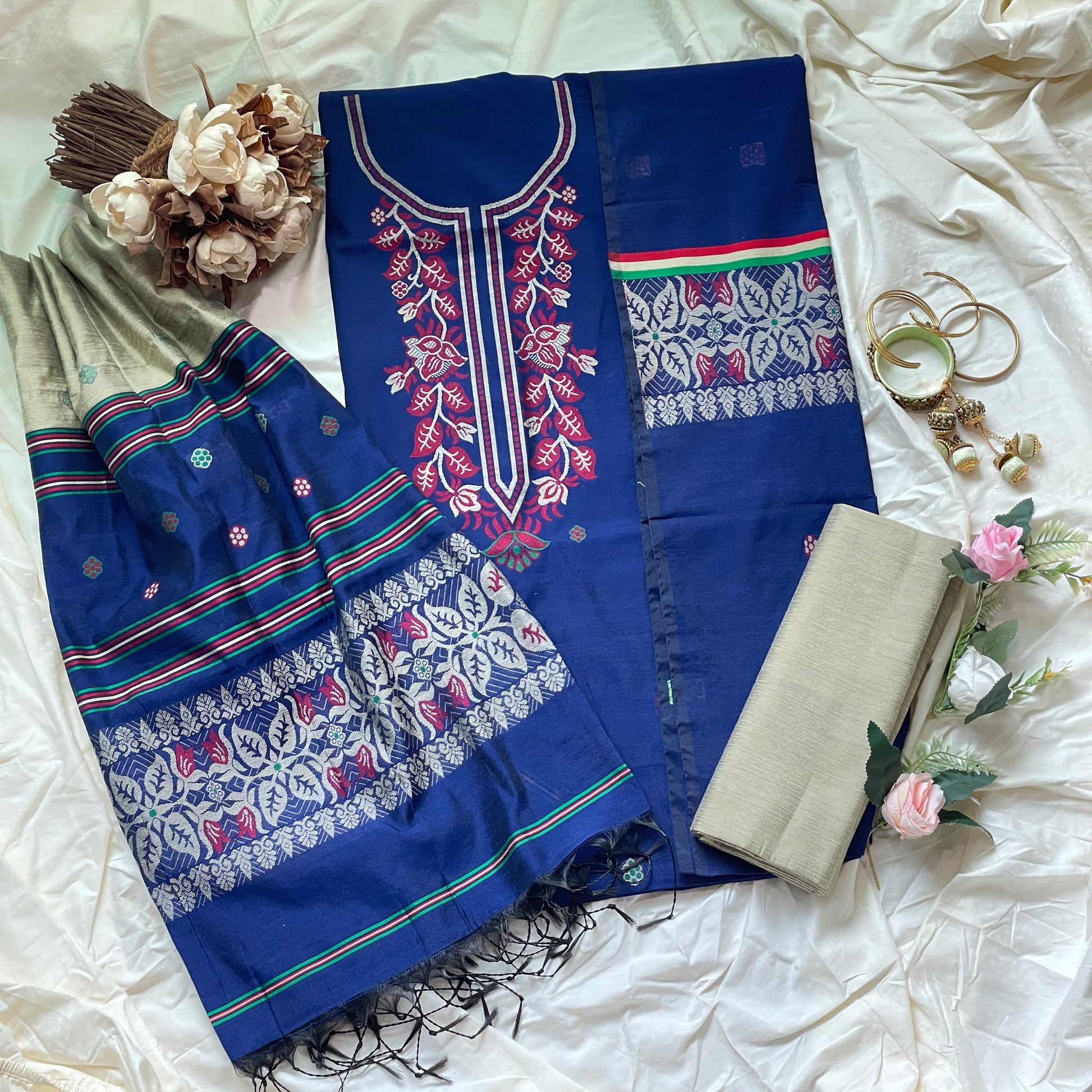 Blue embroidered fabric with floral patterns on a white surface with decorative elements.